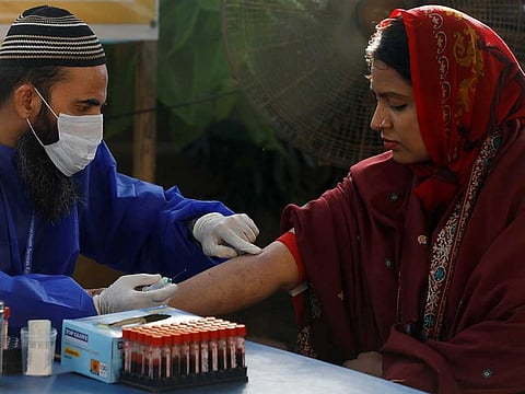 A paramedic wearing protective gloves prepares to take a blood sample from a woman, to be tested for the coronavirus disease (COVID-19) anti-body test, at a camp in Karachi, Pakistan July 24, 2020.