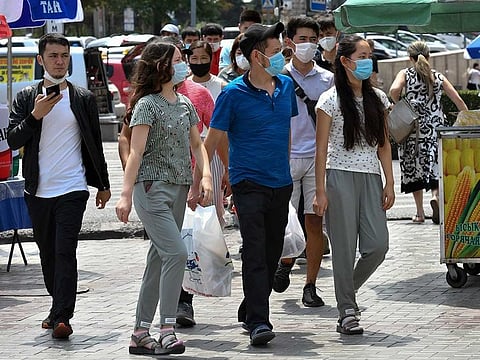 Youths in face masks walk through a street market in Bishkek, Kyrgyzstan, Friday, July 24, 2020.