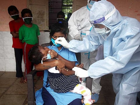 Health workers in personal protective equipment (PPE) collect a nasal sample from a child during a check-up campaign for the coronavirus disease (COVID-19), at a children's home in Mumbai on Tuesday.