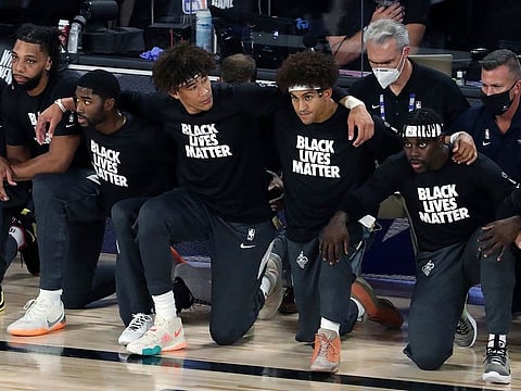 New Orleans Pelicans players kneel and lock arms during the national anthem before an NBA basketball game against the Utah Jazz, Thursday, July 30, 2020, in Lake Buena Vista, Florida.