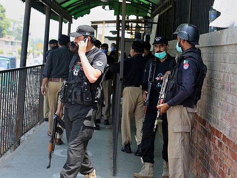 Police officers gather at an entry gate of district court following the killing of Tahir Shamim Ahmad, who was in court accused of insulting Islam, in Peshawar, Pakistan, Wednesday, July 29, 2020.