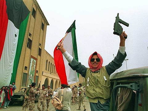 A member of the Kuwaiti resistance raises his rifle and the national flag in celebration as Kuwaiti's filled the streets on February 28, 1991, after US President George Bush's announcement of a ceasefire.