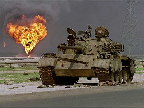 An abandoned Iraqi Soviet-made T-62 tank sits in the Kuwaiti desert as an oil well at Al Ahmadi oil field is burning in the background, on April 2, 1991.