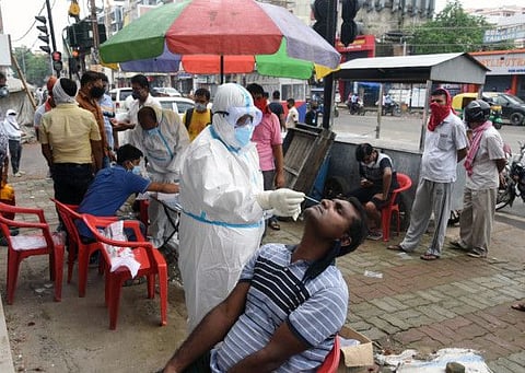 A health worker wearing PPE collects samples from a man for COVID-19 rapid antigen testing, in Patna on Thursday.