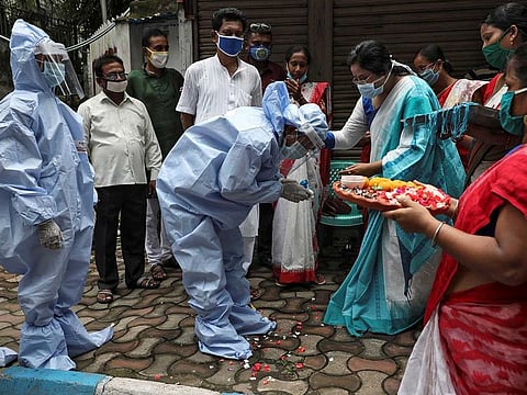 A woman ties a Rakhi, traditional Indian sacred thread, on the wrist of a municipal worker wearing personal protective equipment (PPE) to celebrate the Hindu festival of Raksha Bandha, during which a sister ties one or more of the sacred threads onto her brother's wrist to ask him for her protection in Kolkata, India, August 3, 2020.