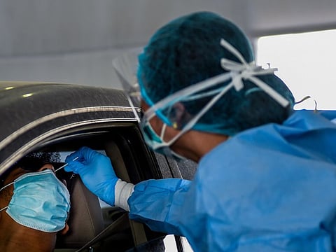 Paramedics collect swab samples at a drive-through screening station for coronavirus in Sharjah.