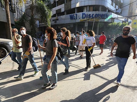 Volunteers carry brooms as they walk to clean the streets, following Tuesday's blast in Beirut's port area, Lebanon.
