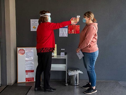 A patient has her temperature checked at a medical clinic during lockdown due to the continuing spread of the coronavirus in Melbourne, Thursday, Aug. 6, 2020. Victoria state, Australia's coronavirus hot spot, announced on Monday that businesses will be closed and scaled down in a bid to curb the spread of the virus.