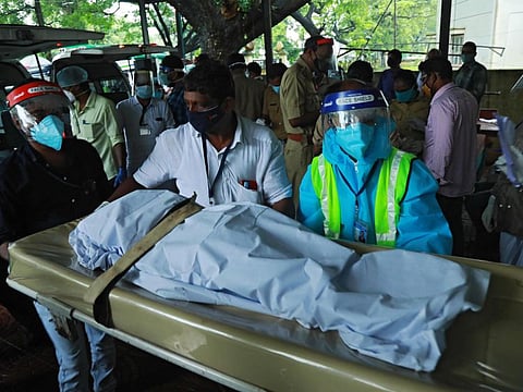 Medical staff wearing Personal Protective Equipment (PPE) equipment carry the body of a victim inside the medical college where victims of the Air India Express jet crash victims are taken for post-mortem in Kozhikode, Kerala, on August 8.