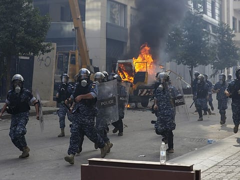 Lebanese security forces run towards protesters during a protest against the political elites and the government after this week's deadly explosion at Beirut port which devastated large parts of the capital in Beirut, Lebanon, Saturday.
