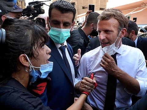 French President Emmanuel Macron (right) speaks with a woman on August 6, 2020, during a visit to the Gemayzeh neighbourhood, which suffered extensive damage from the August 4 explosion that hit the seaport of Beirut, Lebanon.
