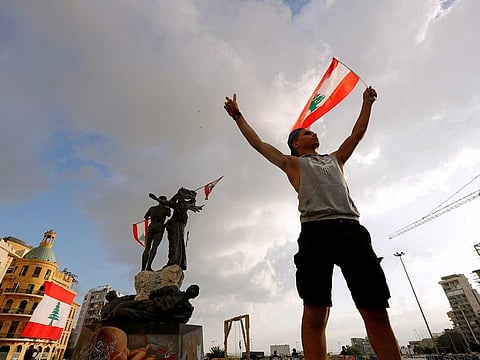 A demonstrator holds the Lebanese flag in Martyrs’ Square where protests are held on August 9, 2020, following Tuesday’s blast in Beirut, Lebanon.