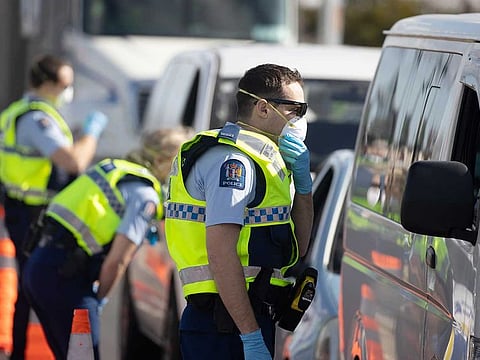 Police officers wearing protective masks talk to motorists at a checkpoint in the Bombay area of Auckland, New Zealand, on Wednesday, Aug. 12, 2020. New Zealand’s world-beating run of being COVID-19-free has come to an end, with the detection of new cases prompting the government to put largest city Auckland into lockdown.