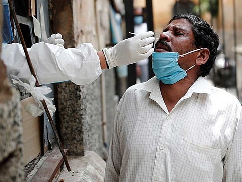 A health worker in personal protective equipment (PPE) collects a sample using a swab from a person at a local health centre to conduct tests for the coronavirus disease (COVID-19), amid the spread of the disease, in the old quarters of Delhi, India, August 14, 2020.