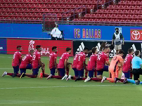 Reggie Cannon, No. 2, and his Dallas teammates kneel during the national anthem