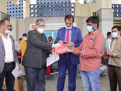 From left: S.V. Reddy, Hussain Nalwala and E.P. Johnson see off stranded Indian workers whose repatriation tickets were sponsored by Nalwala, at Sharjah International Airport last Friday.