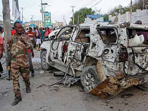 A member of the security forces walks past a wrecked vehicle outside the Elite Hotel in Mogadishu, Somalia Monday, Aug. 17, 2020.