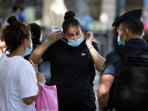 A resident puts on a face mask as a French riot police officer informs her of the mandatory face mask requirement in Marseille, southern France, Tuesday, Aug.18, 2020. The French government is sending riot police to the Marseille region to help enforce mask requirements, as more and more French towns and neighbourhoods are imposing mask rules starting Monday to slow rising infections.