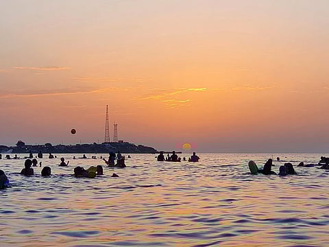 People bathe in the Mediterranean sea water off a beach in Libya's capital Tripoli near sunset on August 18, 2020.