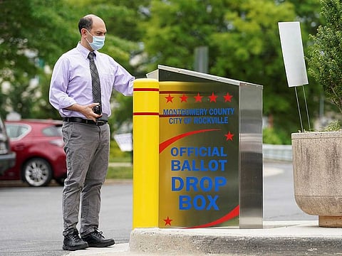 A man wearing a mask to prevent the spread of coronavirus disease (COVID-19) casts his ballot for Maryland's primary election at a drop box in Rockville, Maryland, US, June 2, 2020.