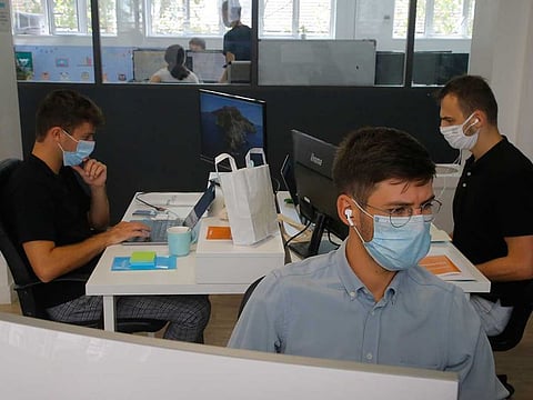 Employees wear a mask in a startup company, Wednesday Aug.19, 2020 in Paris. France is now mandating masks in all workplaces, from the Paris business district to factories in the provinces to contain the spread of the coronavirus.