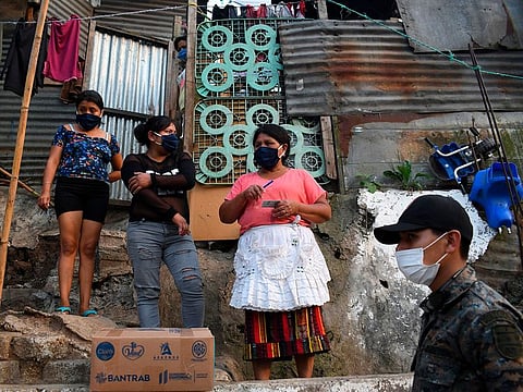 Guatemalan soldiers wearing face masks as a preventive measure against the spread of new coronavirus, COVID-19, distribute boxes with food supplies at Las Brisas del Lago neighborhood during a partial curfew ordered by the government, in Villa Nueva, 20 km south Guatemala City.