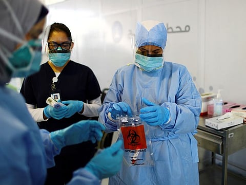 A medical staff member carries a swab sample for testing at a screening centre in Abu Dhabi.