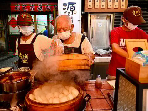 80-year-old Wu Huang-yi, owner of Yuan Fang Gua Bao restaurant, preparing food with his family at the Huaxi Night Market in the Wanhua district in Taipei.