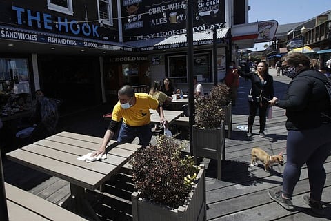 A man wears a face mask while cleaning an outdoor dining table (File image)