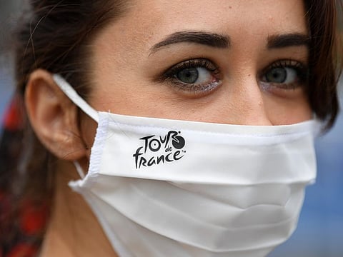 A woman wears a protective face mask with the Tour de France logo at the start.