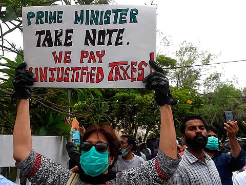 A resident of Defence Housing Authority (DHA), holds a placard as they gather outside the Cantonment Board Clifton (CBC) office to protest against the failing to fix drainage problems in the city following heavy monsoon rains triggered floods in Pakistan's port city of Karachi on August 31, 2020.