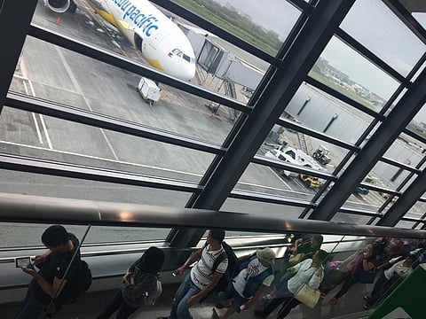 Passengers queue up to board a Cebu Pacific aircraft at Manila's Ninoy Aquino International Airport.