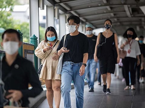 Commuters wearing protective masks walk along a pedestrian bridge in Bangkok, Thailand.