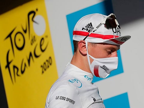 UAE Team Emirates' Tadej Pogacar in front of the Tour De France logo.