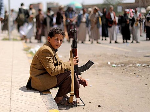 A boy sits at the site of a rally held by followers of the Al Houthi militia in August 2020.