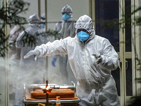 Health workers and relatives prepare for a funeral of a COVID-19 patient, in Kozhikode, Kerala.