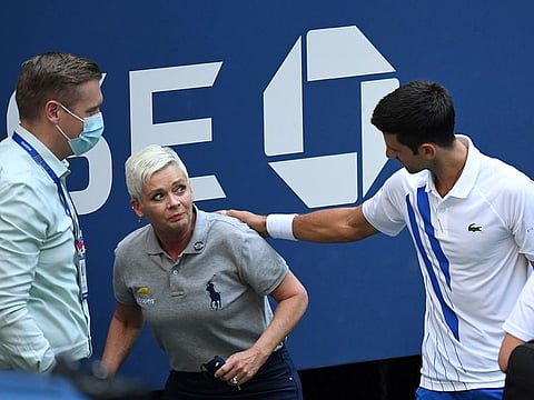 Novak Djokovic comes to the line judge's aid after hitting her with a ball at the US Open