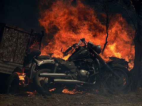 Flames burn near a motorcycle during a wildfire in Kalyvia, southeast of Athens, on Wednesday, Sept. 9, 2020. Greek firefighters, backed by water-dropping aircraft, were battling a string of wildfires near Athens and in other parts of the country Wednesday with efforts hampered by strong winds that whipped on the flames