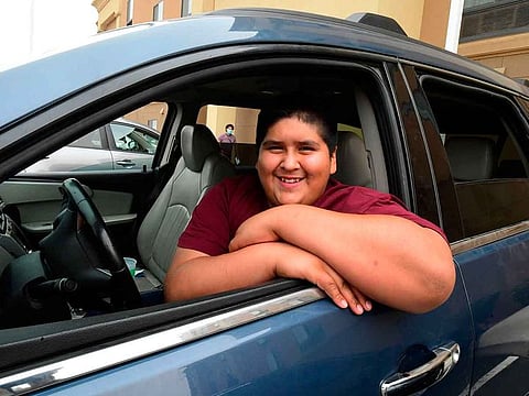 Ruben Navarette, 14, poses at the wheel of the vehicle he had to drive for the first time when escaping the Creek Fire on Labour Day from his home in Tollhouse, California.