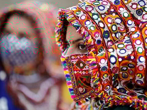 A participant in a traditional costume wearing a face mask attends a rehearsal for Garba, a folk dance, ahead of Navratri.