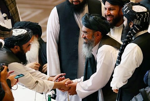 Taliban delegates shake hands during talks between the Afghan government and Taliban in Doha, Qatar on September 12, 2020.