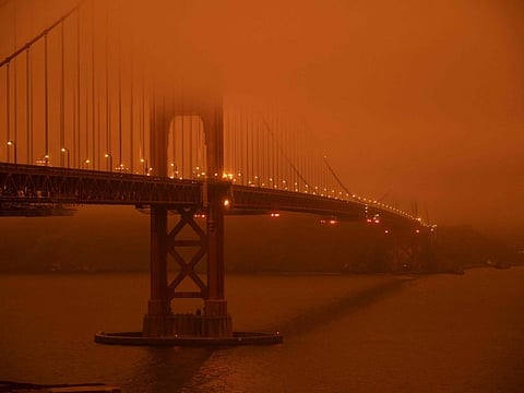 Cars drive along the Golden Gate Bridge under an orange smoke filled sky at midday in San Francisco, California on September 9, 2020.