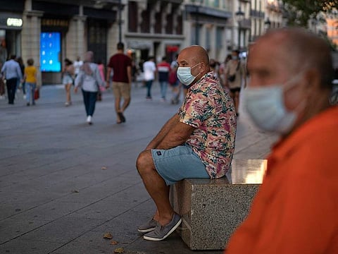 Men wearing face masks to prevent the spread of coronavirus sit in a street in downtown Barcelona, Spain, Tuesday, Sept. 15, 2020. Spain's official death toll for the new coronavirus on Tuesday surpassed 30,000 fatalities as the country's caseload also increased beyond 600,000, becoming the first European country to overcome that threshold.