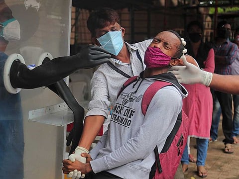 A man reacts as health workers help collect a nasal swab sample to test for COVID-19 in Hyderabad, India, Thursday, Sept. 17, 2020.