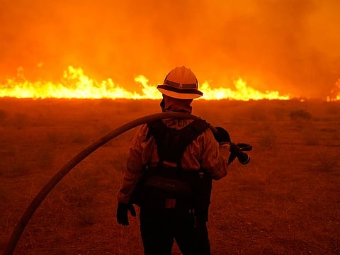 Alexis Miller of Los Angeles County Fire holds a water hose while protecting a home from the advancing Bobcat Fire along Cima Mesa Rd. Friday, Sept. 18, 2020, in Juniper Hills, California.