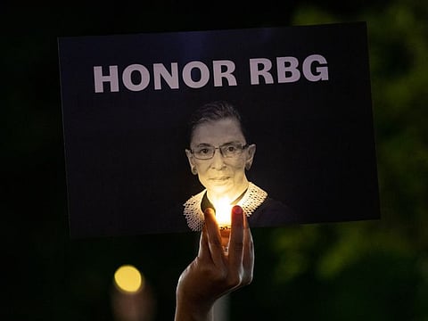 A mourners holds up a sign at a makeshift memorial during a vigil for Supreme Court Justice Ruth Bader Ginsburg outside of the Supreme Court in Washington, DC on Saturday.