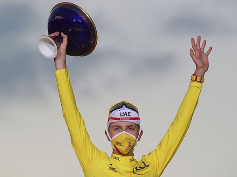 Slovenia's Tadej Pogacar, wearing the overall leader's yellow jersey, celebrates next to his two other jersey's, the best climber's dotted jersey and the best young rider's white jersey, on the podium after the twenty-first and last stage of the Tour de France cycling race over 122 kilometers (75.8 miles), from Mantes-la-Jolie to Paris, France, Sunday, Sept. 20, 2020. (AP Photo/Christophe Ena)