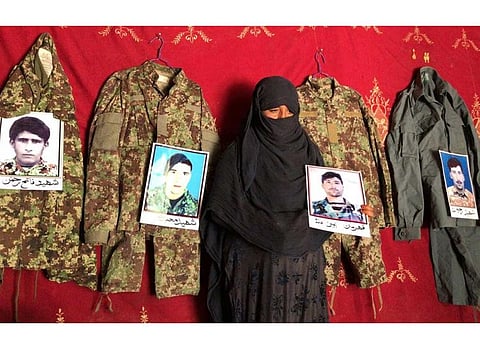 Taj Bibi 33, holds a photo of her husband next to the military uniforms and pictures of her former husbands who were killed battling the Taliban, at her home in Asad Abad, Kunar province, Afghanistan September 20, 2020.
