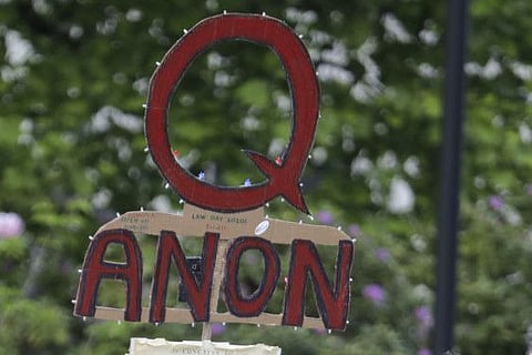 In this May 14, 2020 file photo, a person carries a sign supporting QAnon at a protest rally in Olympia, Wash. Walmart, Amazon and other corporate giants donated money to a Tennessee state lawmaker’s re-election campaign after she used social media to amplify and promote the QAnon conspiracy theory. That's according to an Associated Press review of campaign finance records and online posts by Republican state Rep. Susan Lynn.