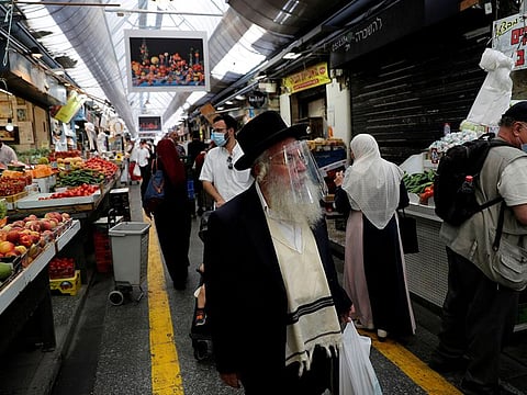 People wear face masks as they shop in a main market in Jerusalem
